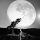 Black and white photograph of a telescope pointing in front of a large moon