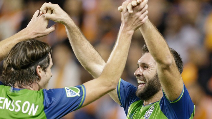 Will Bruin and Gustav Svensson exchange a high-five in their soccer uniforms.