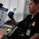 A traveler is fingerprinted while a border agent checks his paperwork.
