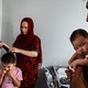 A mom ties her daughter's hair into a ponytail while a father holds their son.