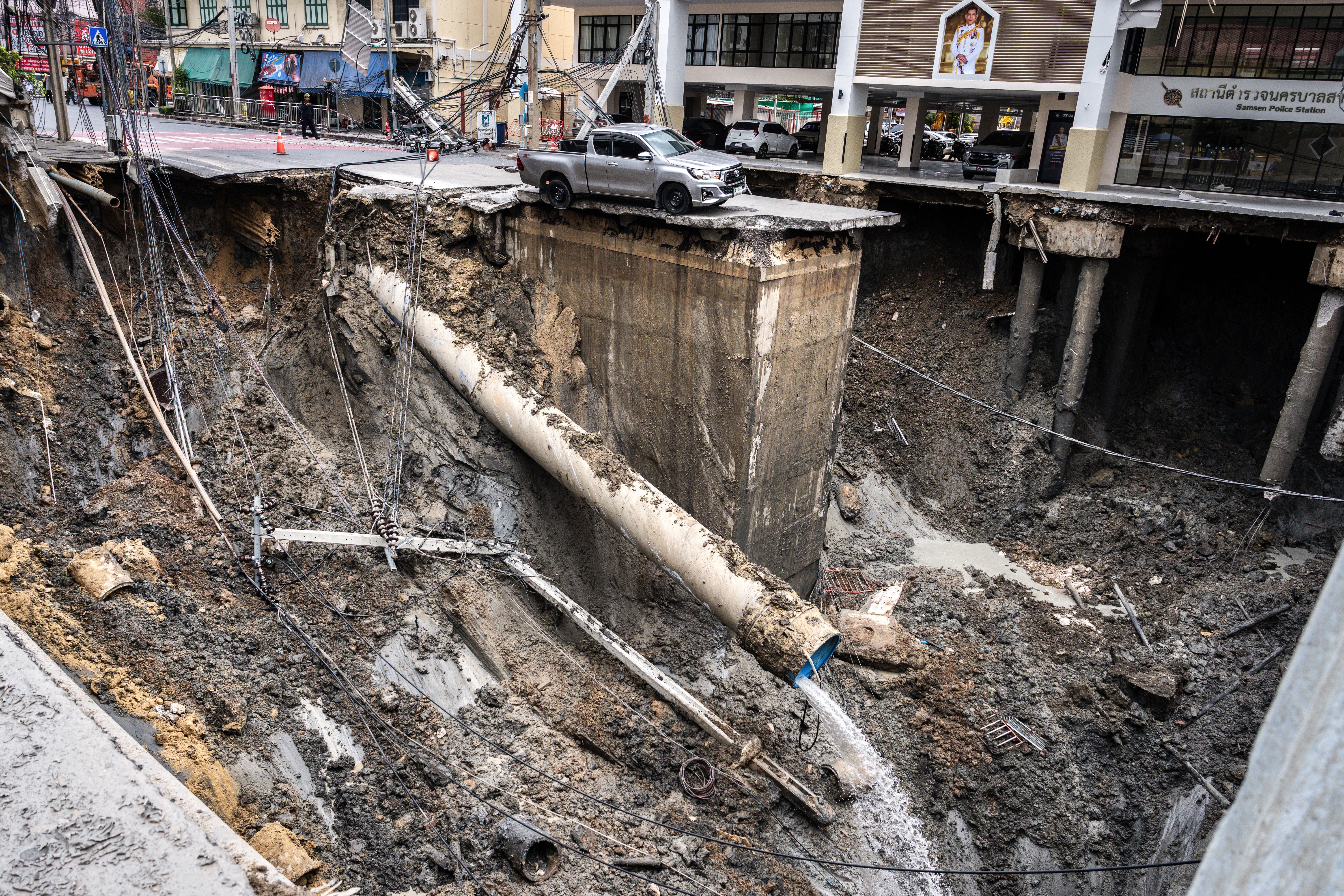A vehicle sits on the edge of a huge hole in the ground after a road collapsed.