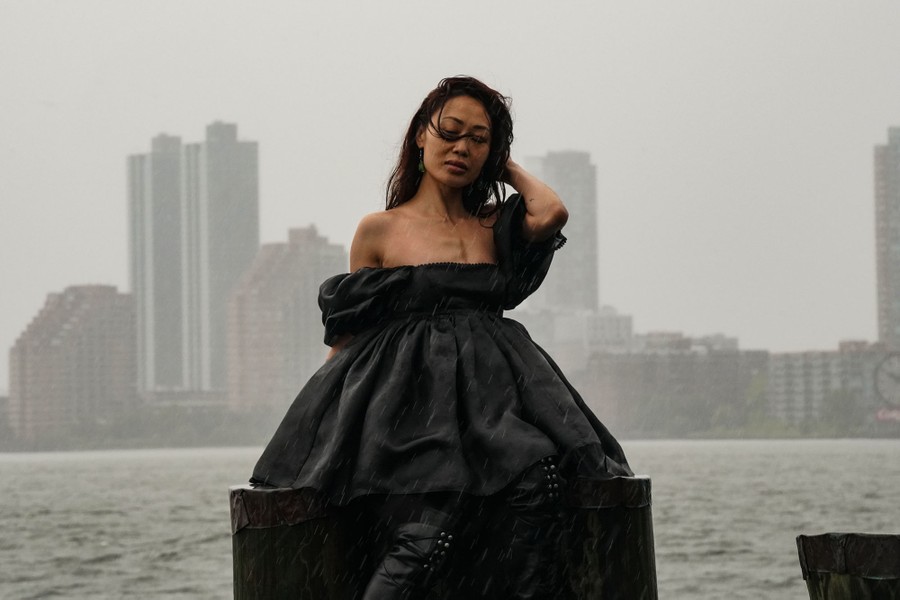 A woman poses for a photo at a waterfront during a storm.
