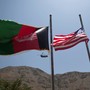 An Afghan flag flutters next to a U.S. flag  with a U.S. military helicopter in the background.