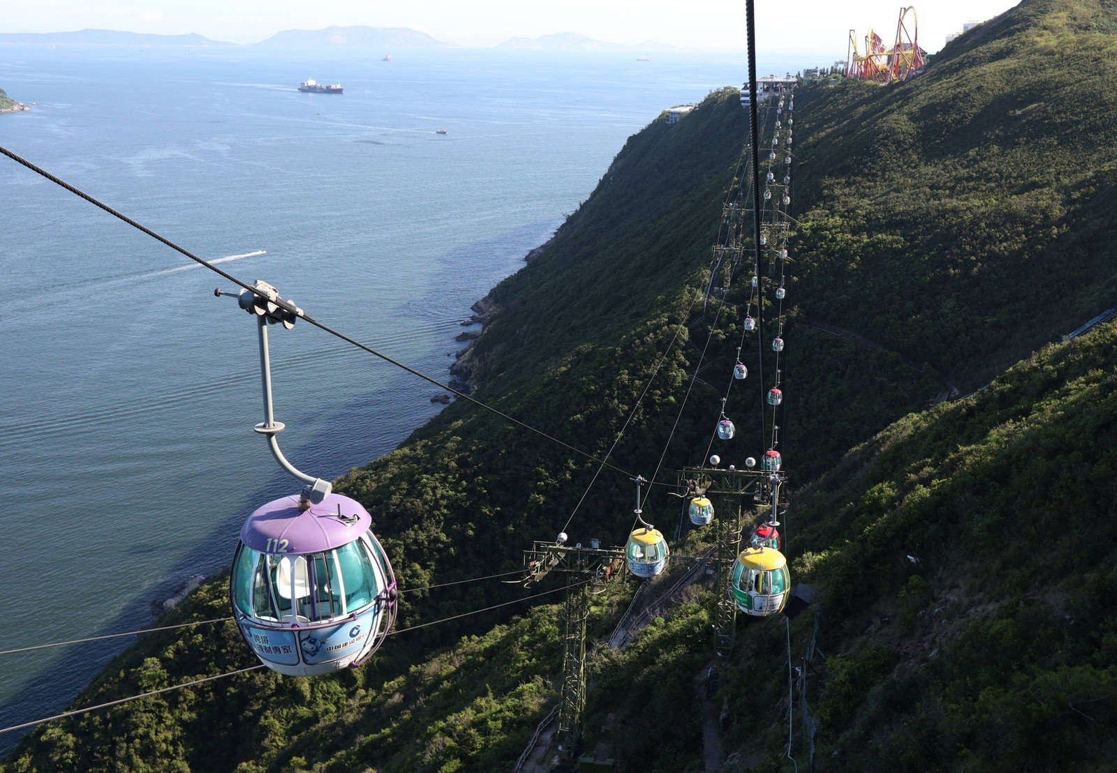 A line of cable cars runs alongside steep mountain slopes in Hong Kong.