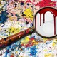 A bloody magnifying glass on top of a paint-splattered background