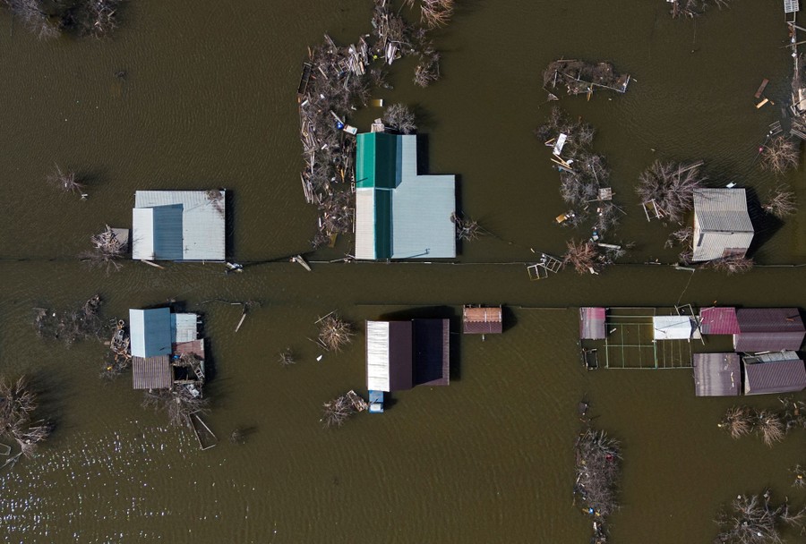 An aerial view of a flooded area, showing the roofs of houses and barns