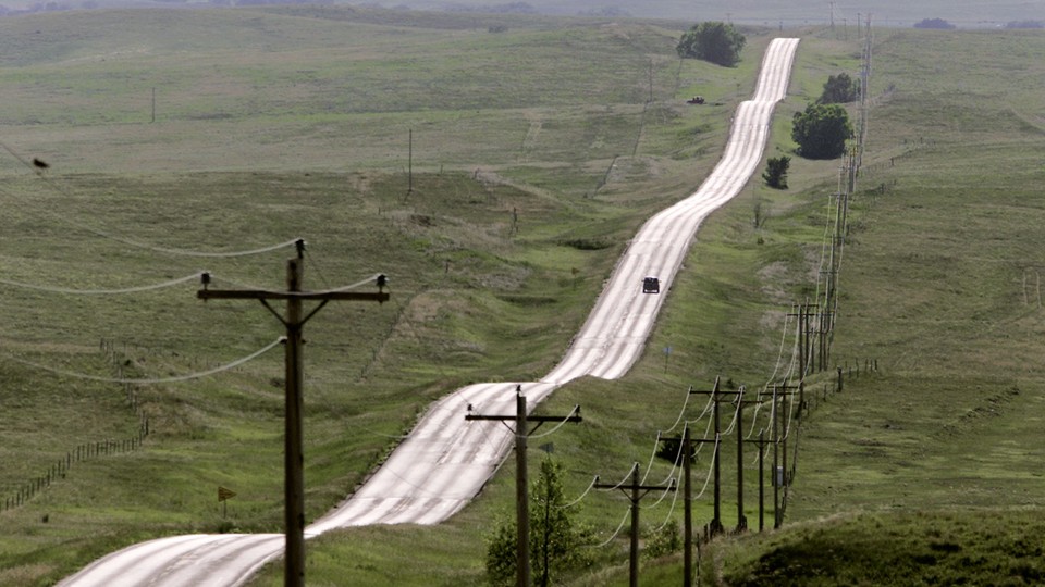 A road surrounded by green hills on the Pine Ridge Indian Reservation, in South Dakota