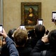A crowd of visitors taking pictures of the "Mona Lisa" painting at the Louvre