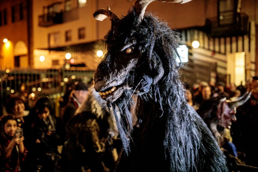 A performer wears a frightening horse-demon costume while walking in a parade.