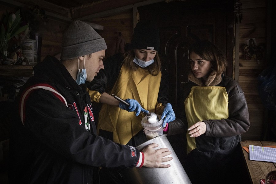 Three people work together to place the last rice they have into a container to hand out.