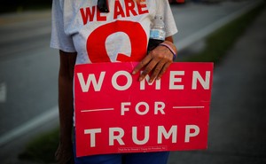 A woman holding a "Woman for Trump" sign.