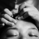 Someone's hands massage a person's forehead.