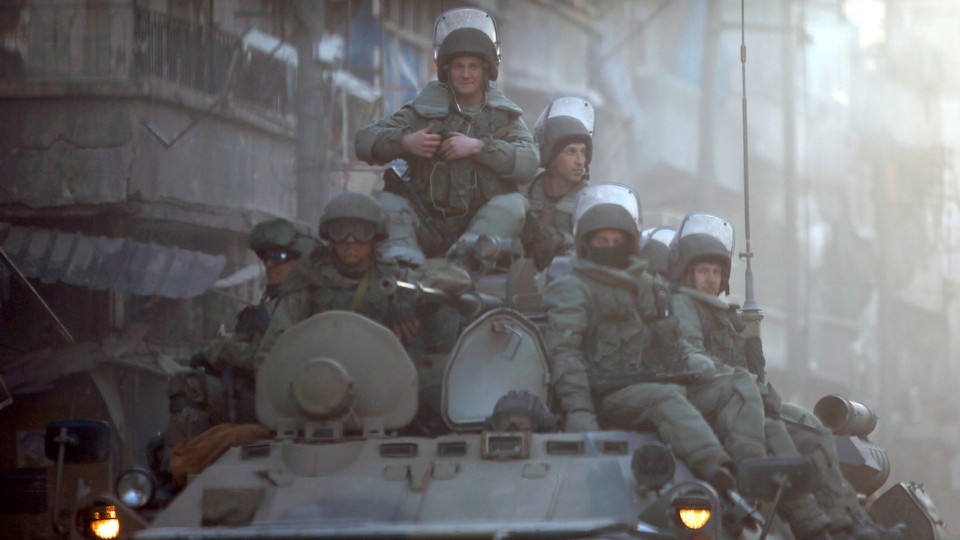 Heavily armed Russian soldiers ride atop an armored tank in Aleppo.