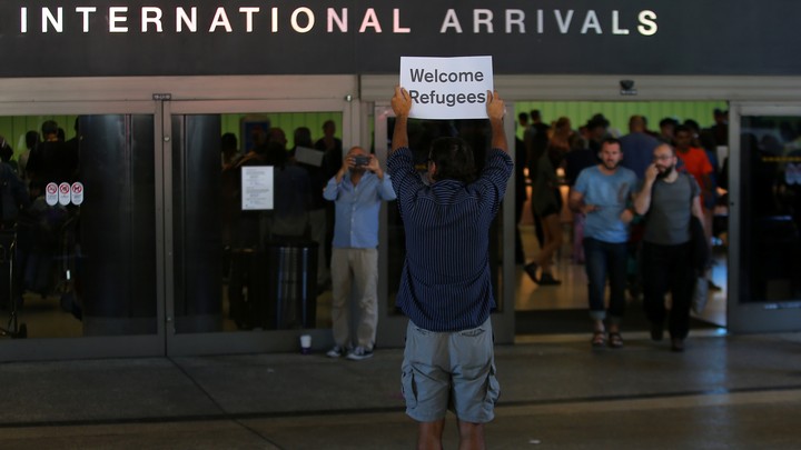 A man holds up a sign welcoming refugees at Los Angeles International Airport