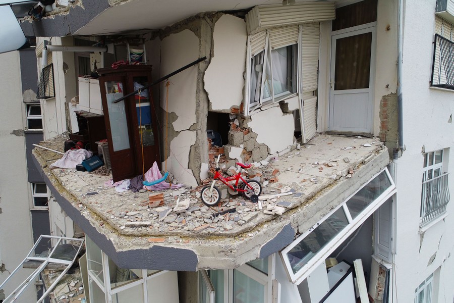 An aerial view of a child's bicycle sitting in a heavily damaged residential building.