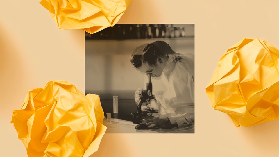 A blurry photo shows a light-skinned scientist in a white lab coat looking into a microscope.