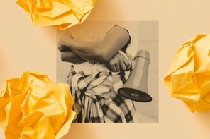 A black-and-white photo shows a person standing with their arms crossed and a megaphone in one hand.