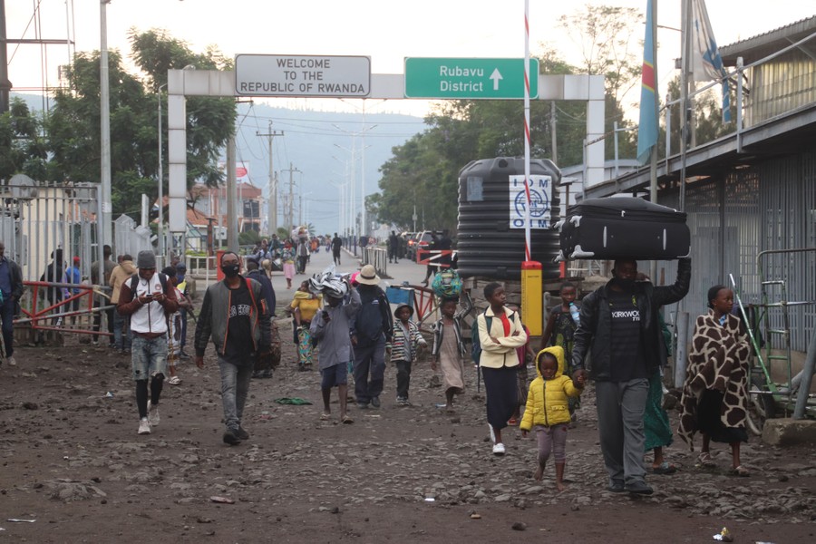 People carry belongings while walking in the street.