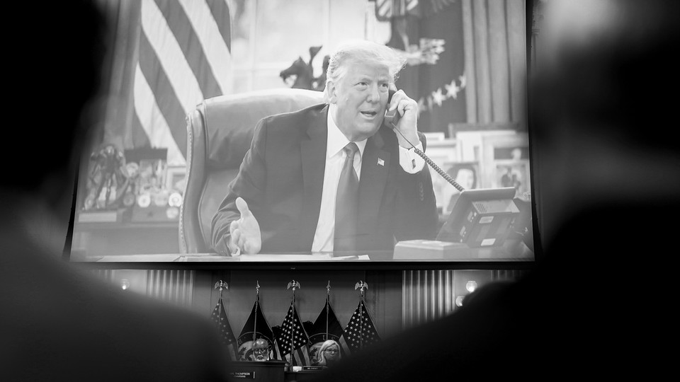 Black-and-white picture of screen showing then-President Donald Trump speaking on the phone from his desk at the Oval Office.