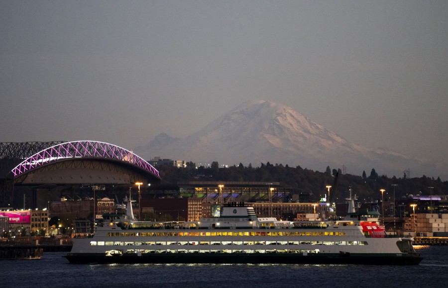 A Washington State ferry comes in to dock at the Seattle ferry terminal, backdropped by Mount Rainier.