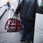 A man carries a bag with the British flag onto a bus.