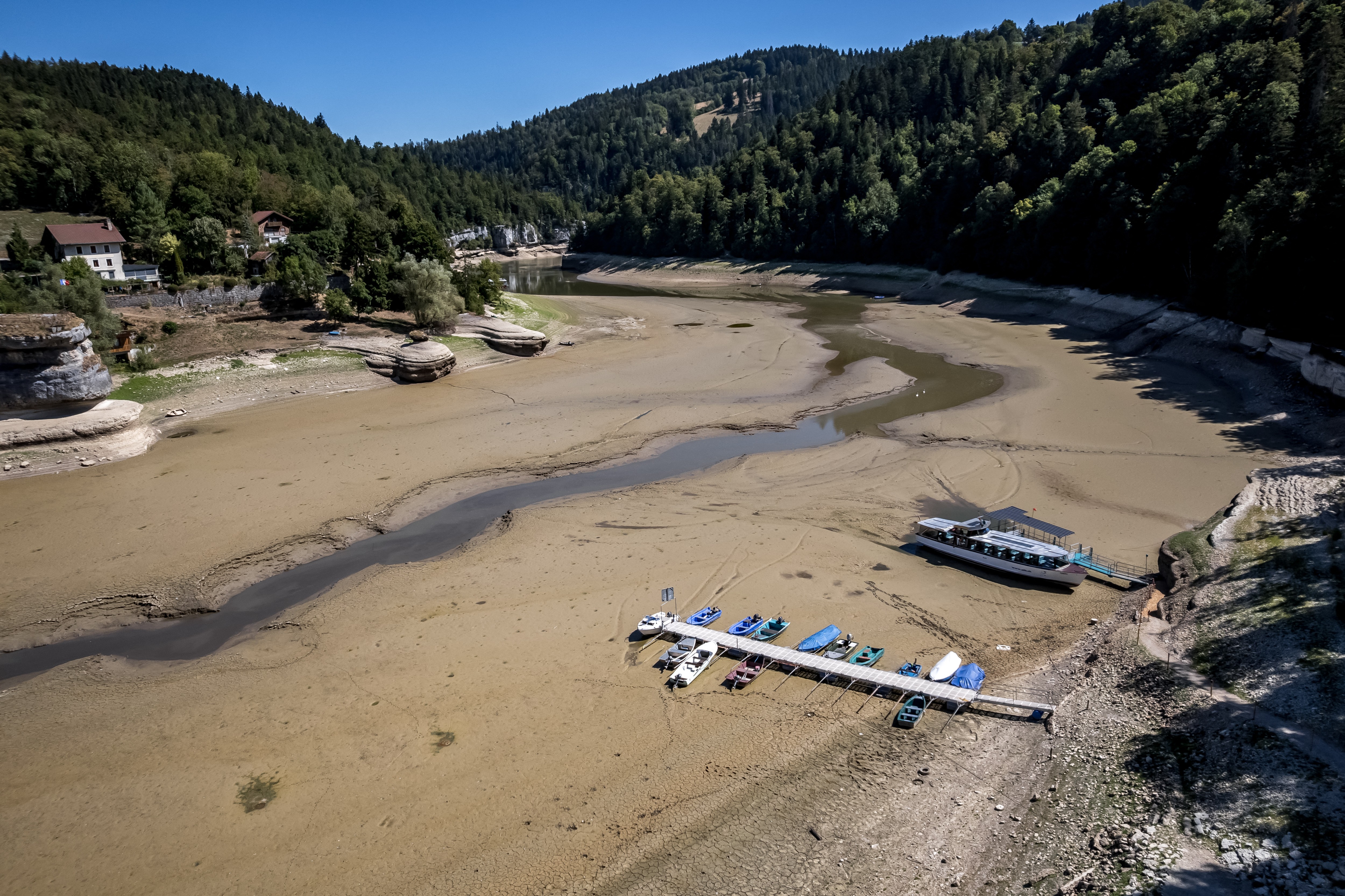 An aerial view of a dried-out lake bed, with boats and floating docks resting on mud