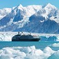 A cruise ship travels in Alaska against a backdrop of fjords and glaciers.