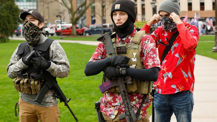 A photograph shows three men standing together—two carry firearms, and two are wearing floral shirts.