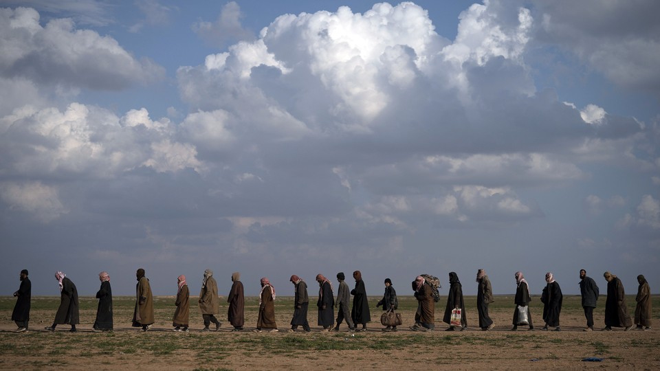 Men wait to be screened following their evacuation from Baghouz, Syria, on February 22.