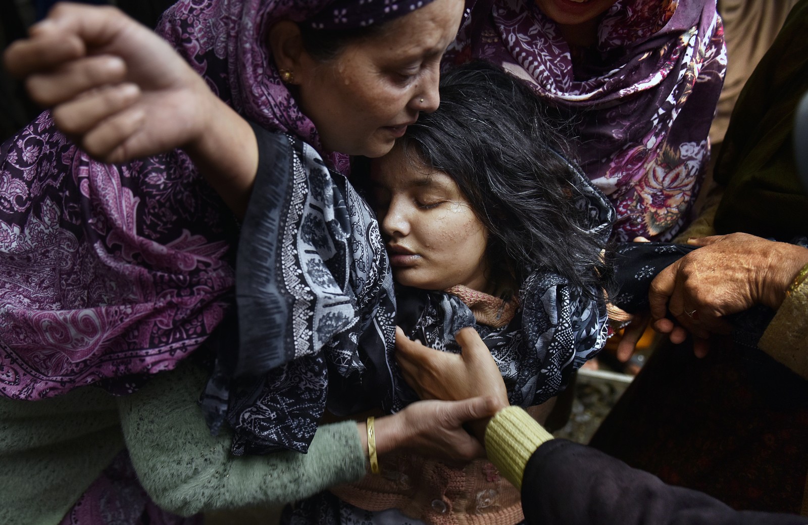 A young woman collapses in grief, held by several others.