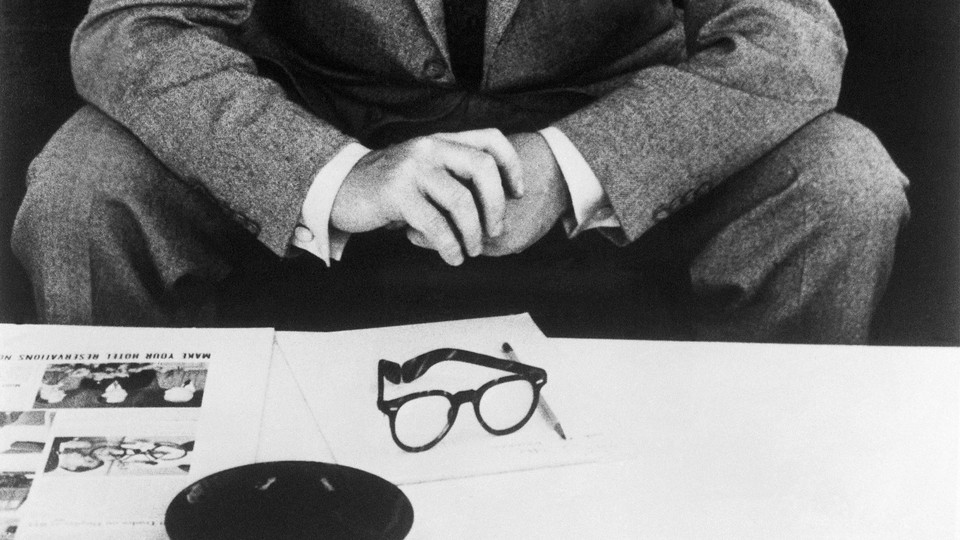 A man in a suit sits in front of papers.