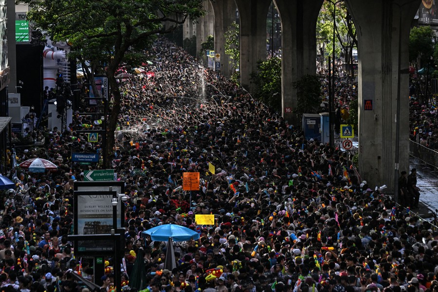 An elevated view of a huge crowd filling a city street, spraying water on each other