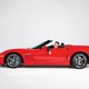 A man site in a red convertible with a sad expression on his face.