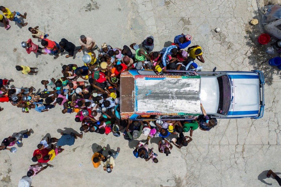 A group of refugees gather around a truck.