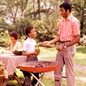 A vintage photo of a Black family sitting around a table and grilling outside