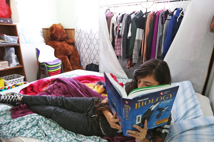 A girl sits on a bed and reads
