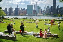 A birthday party in a park on a sunny day, with people relaxing in the background an urban skyline in the distance