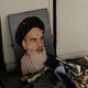 A portrait of Ayatollah Khomeini leaning against a white wall amid rubble and debris