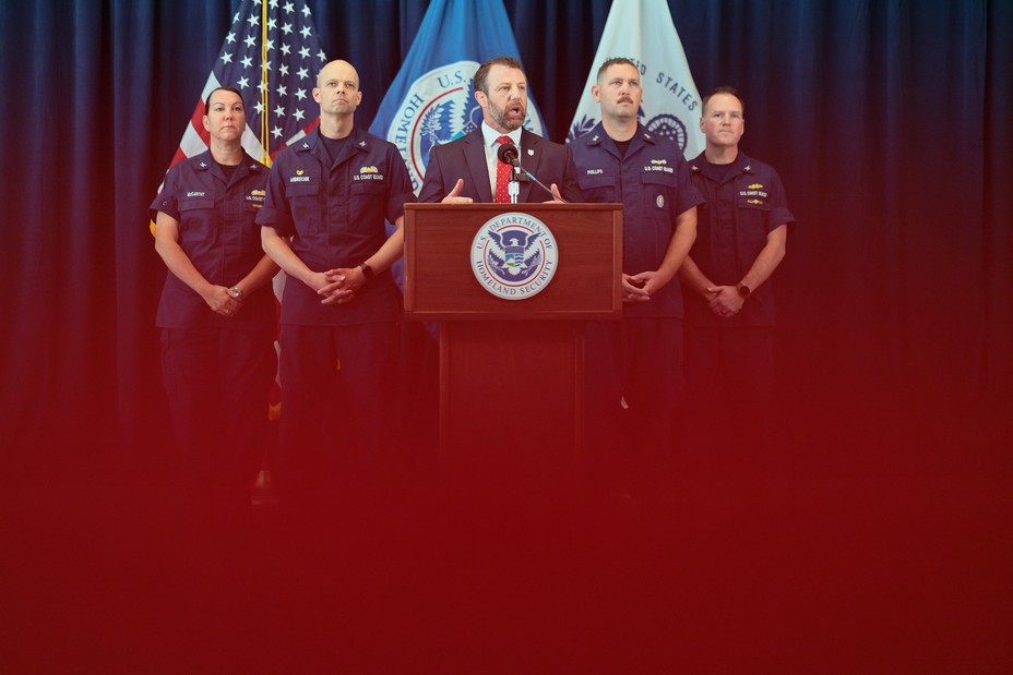 a man speaks at a podium with law enforcement behind him