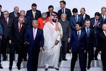 World leaders, most of them men in dark suits, start to disperse from their positions for a group photo