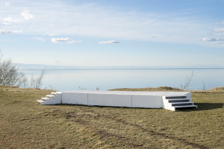 an empty stage in front of a blue sky and lake