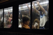 A crowded bus captured from the outside, its many passengers framed by windows