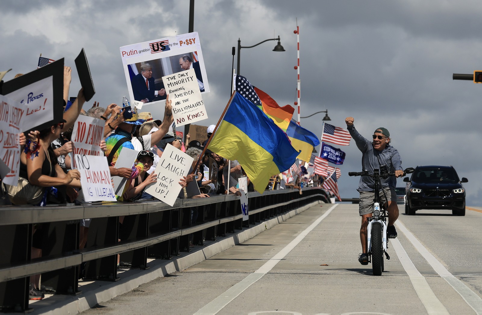 A cyclist raises his fist in support of a line of protesters beside him.