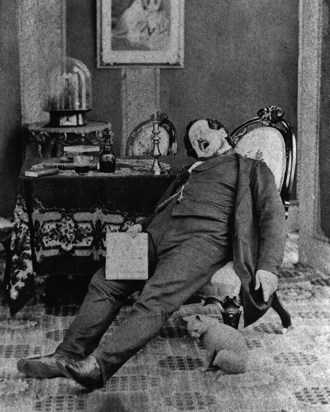 Old, black and white photograph of a man asleep in a chair with his mouth wide open.