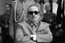 Jaime Vadell wearing sunglasses and a military uniform with arms crossed