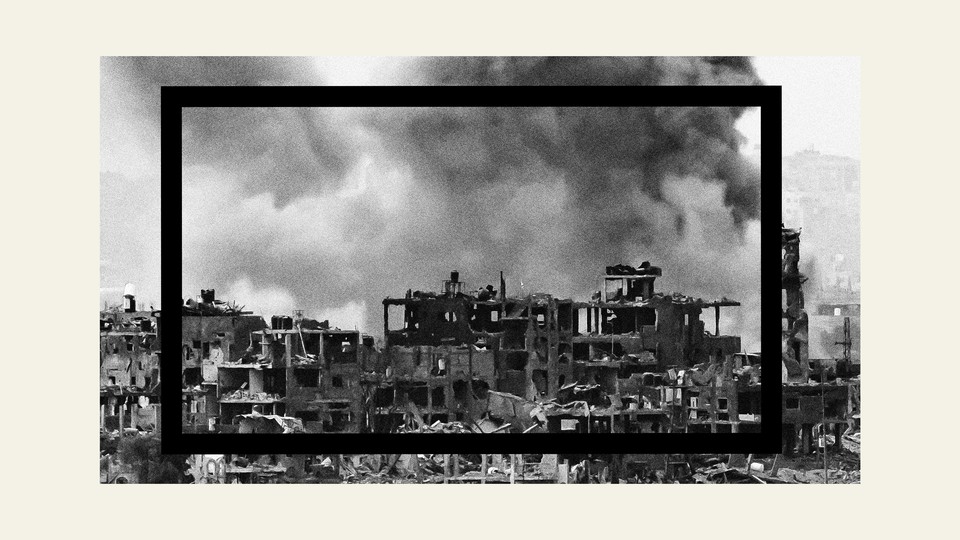 A smoke plume erupts from behind hollowed-out buildings on the Gaza Strip during Israeli bombardment