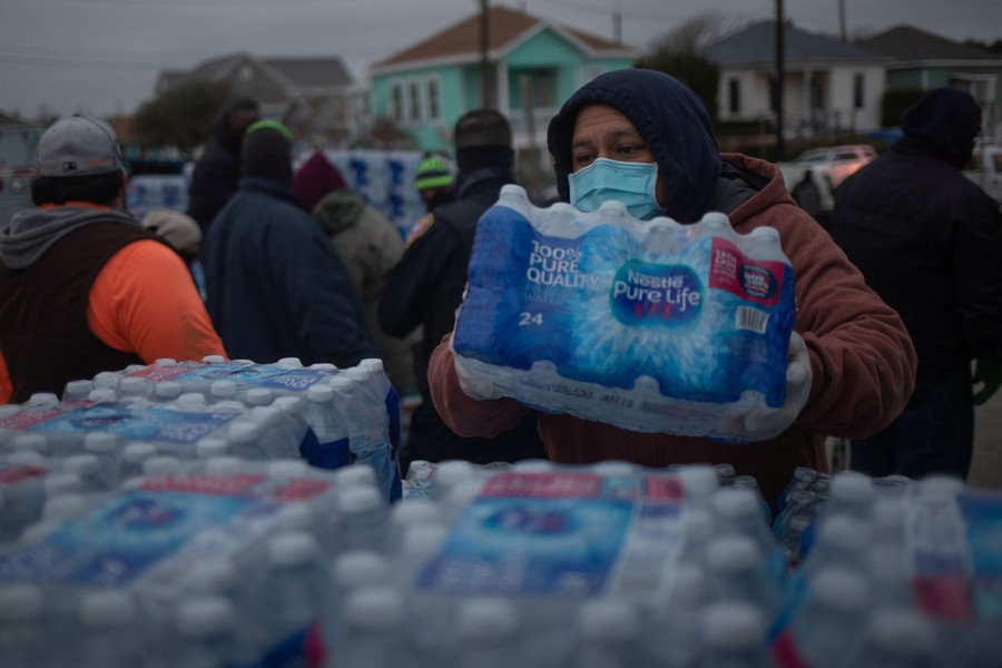 People hand out packs of bottled water in a residential area.