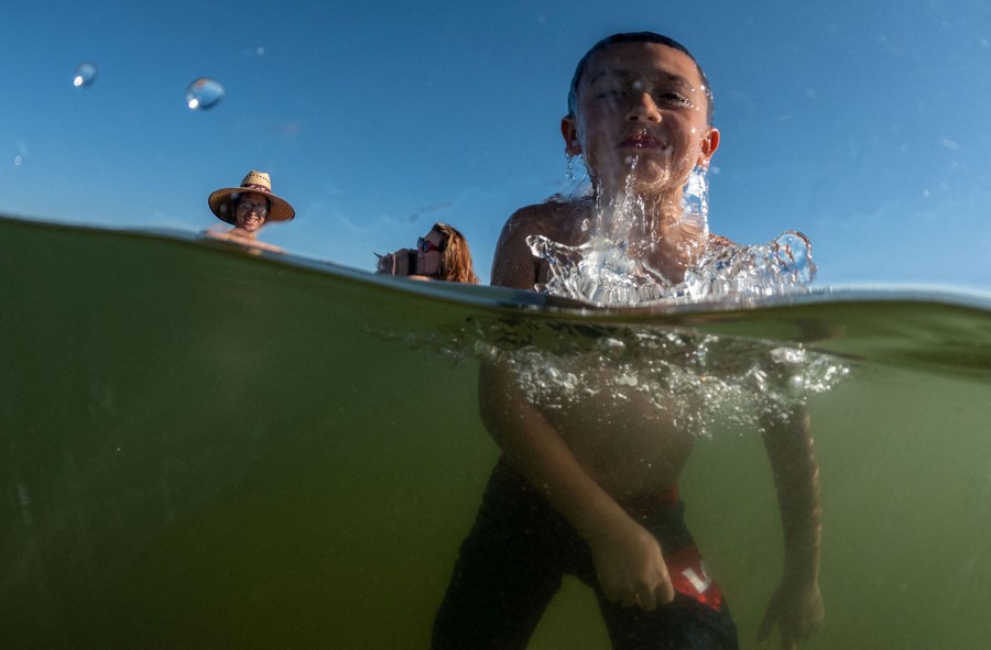 A child plays in a lake, seen both above and below the water.
