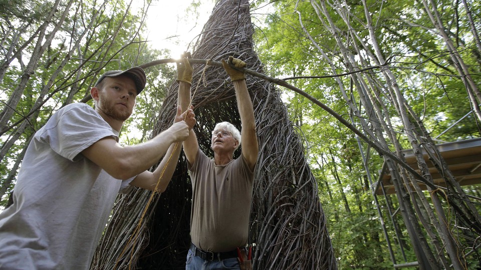 Patrick Dougherty and his son work on a sculpture