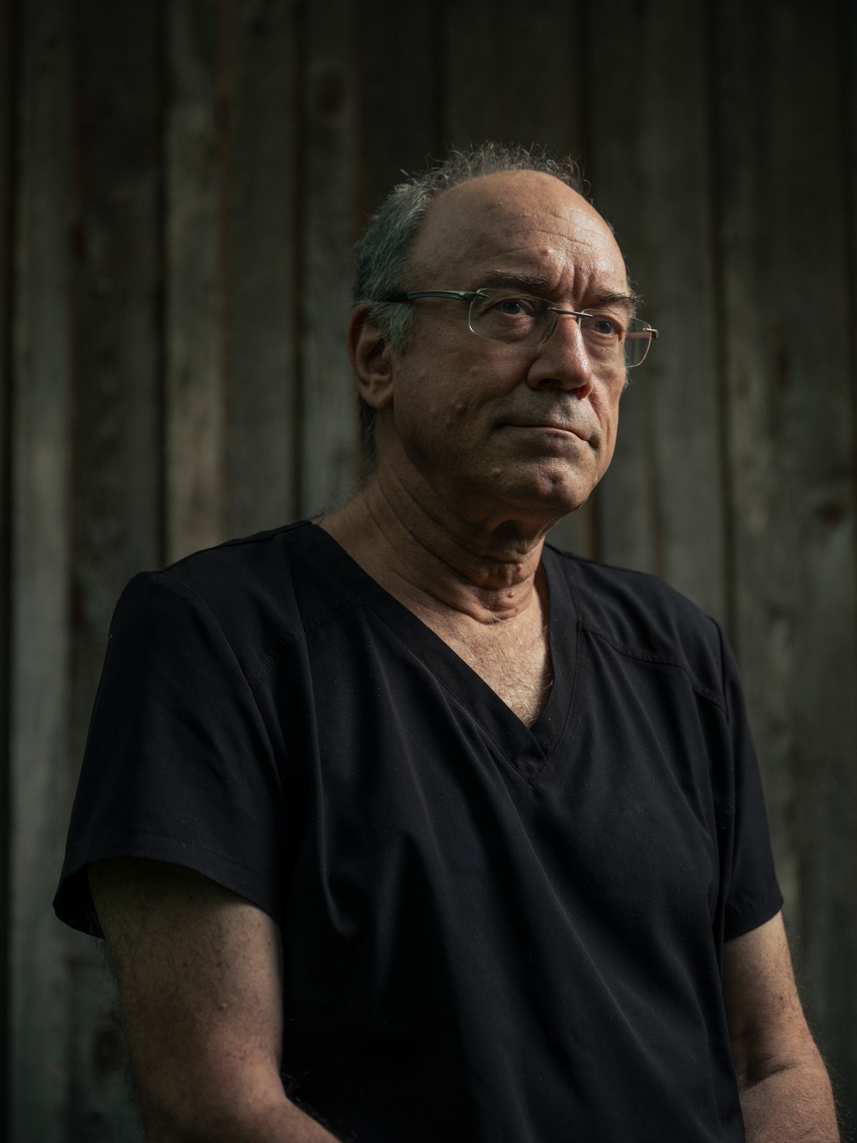 photo of balding man wearing glasses and black v-neck shirt